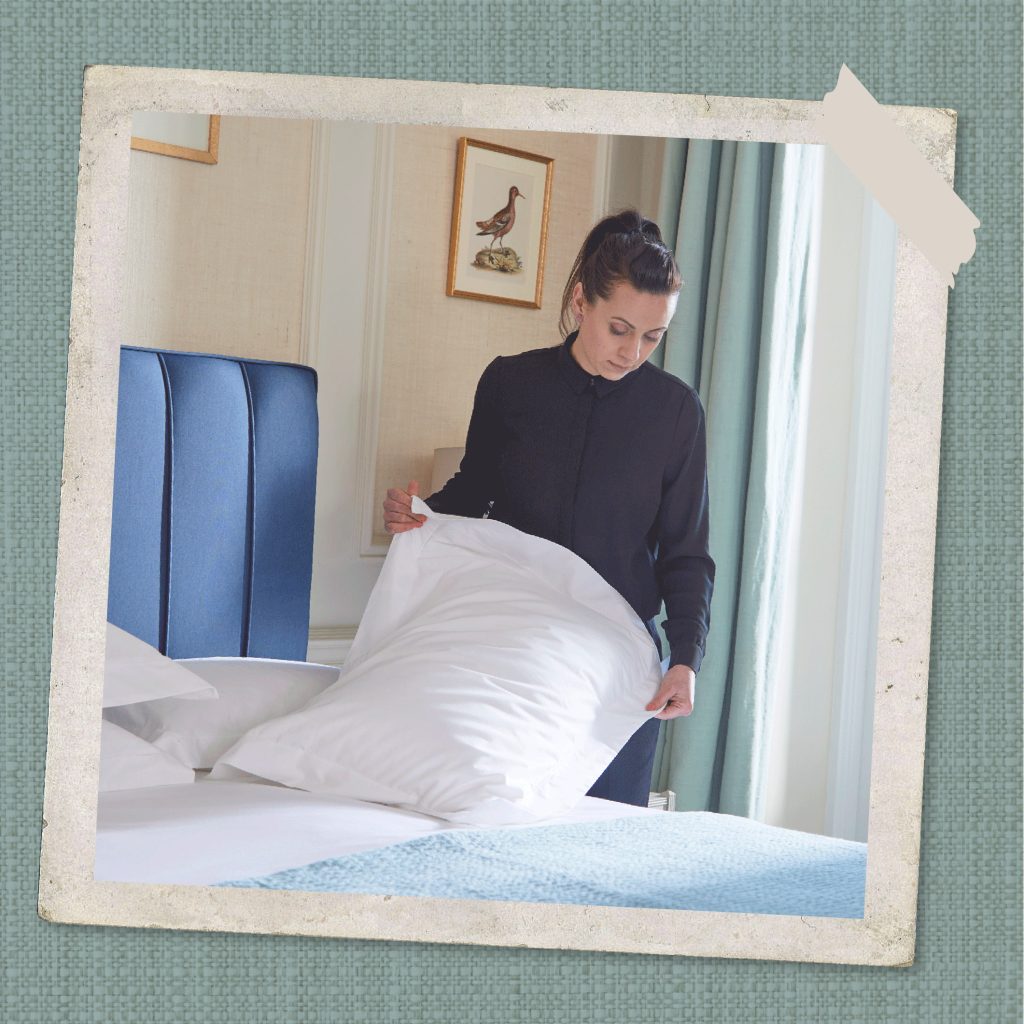 A woman dressed in a dark blouse changing a pillow case